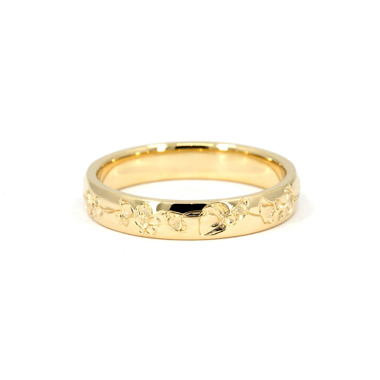 Polished yellow gold wedding band with hand-engraved floral motif, made in Fairmined gold. Available at Ruby Mardi jewelry store in Montreal.