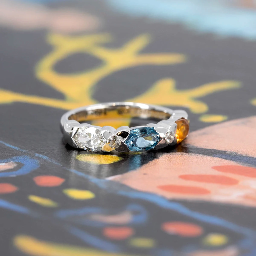 Side view of a Canadian-designed fine jewelry ring in white gold featuring a vibrant mix of citrine, blue topaz, and shimmering diamonds and sapphires, from Ruby Mardi.