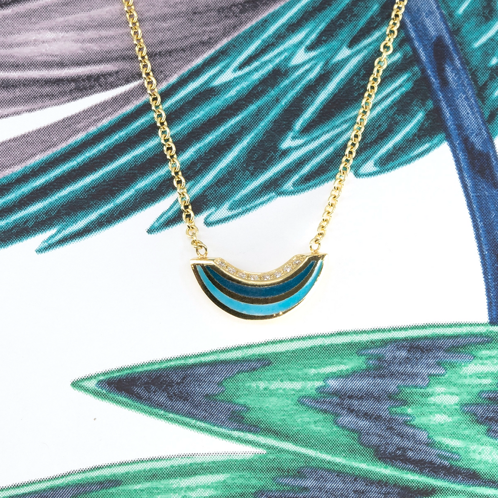 Close-up of Emily Gill’s 14k yellow gold necklace featuring blue enamel and diamonds, sold at Ruby Mardi, a designer jewelry store in Montreal, Canada.