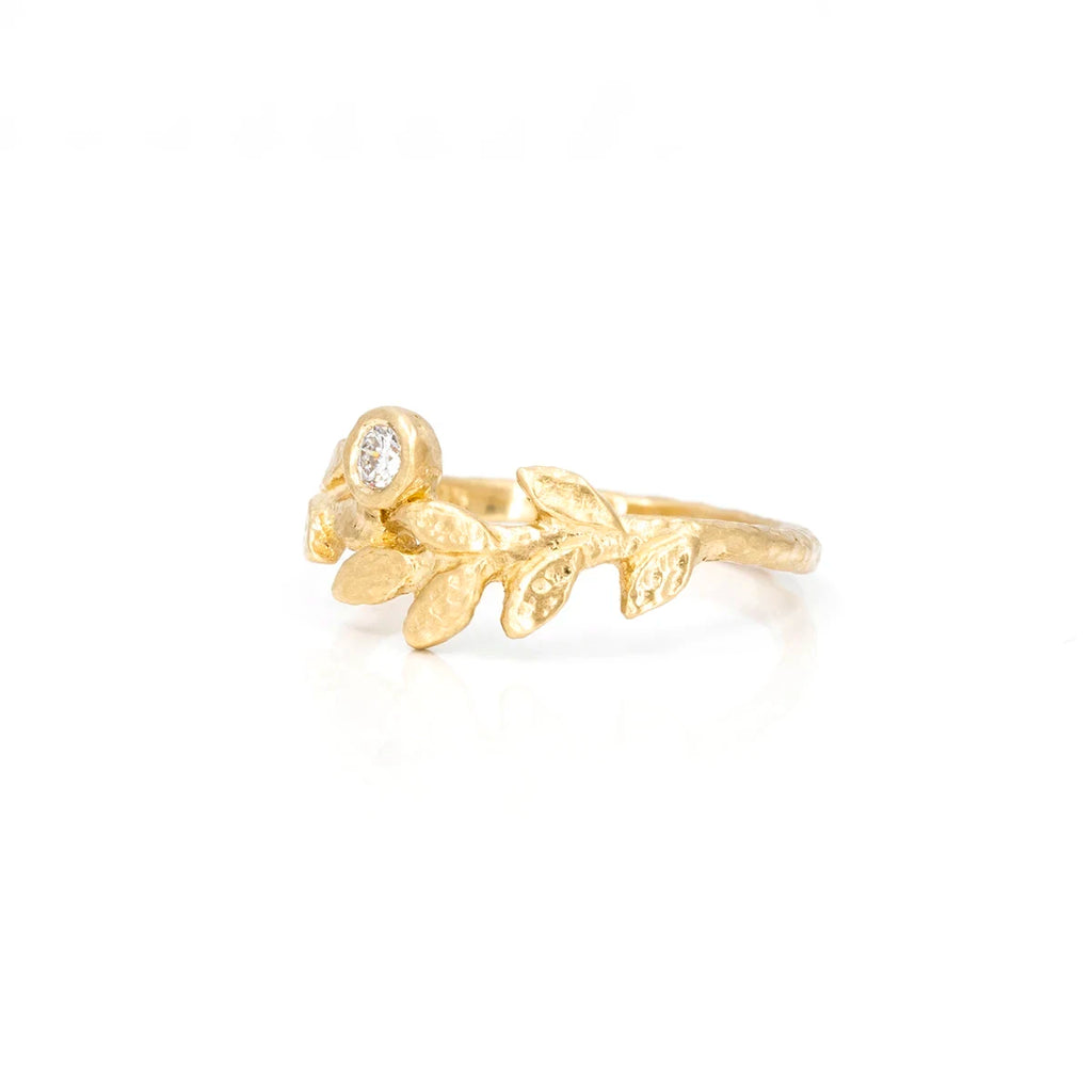 Side view of a textured ring by Anouk Jewelry showcasing a delicate laurel crown design, featuring a round natural diamond, set against a clean white background.