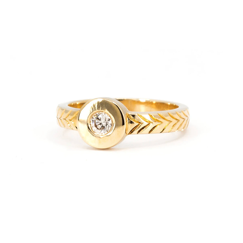 Thick gold signet ring with hand engraved details on the band and a central round champagne diamond. This designer ring from Canadian jewelry designer Savannah Jones is seen photographed on a white background.