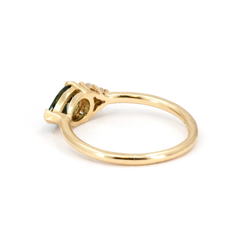Side view of a handcrafted pear-cut teal sapphire engagement ring in yellow gold with intricate detailing and diamond accents. Designed by Sheena Purcell for Ruby Mardi, showcasing expert craftsmanship. Made in Montreal, Canada.