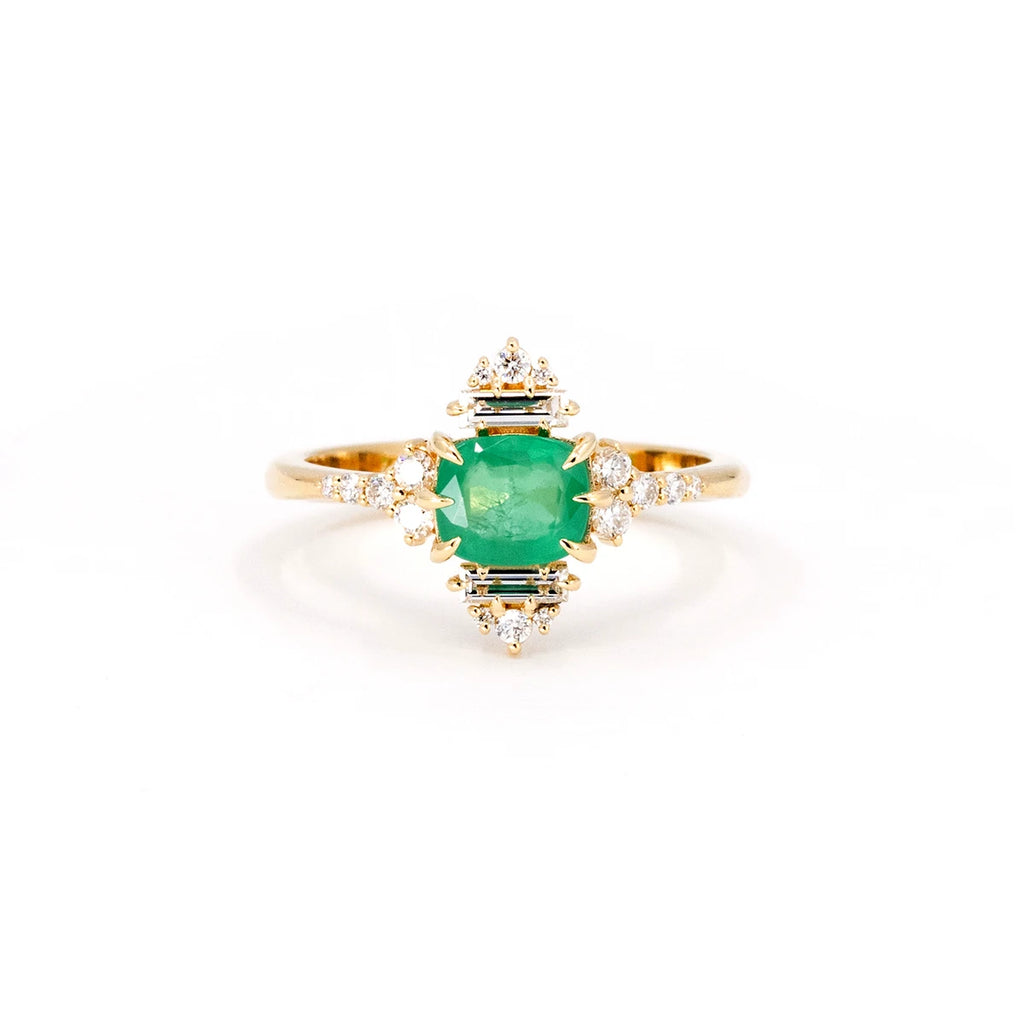 The front view of Oleg Leybman's ring is a custom creation made with a cushion-shaped emerald and natural baguette and round-shaped diamonds. This handmade bridal ring is available for sale at the Ruby Mardi jewelry store based in Montreal.