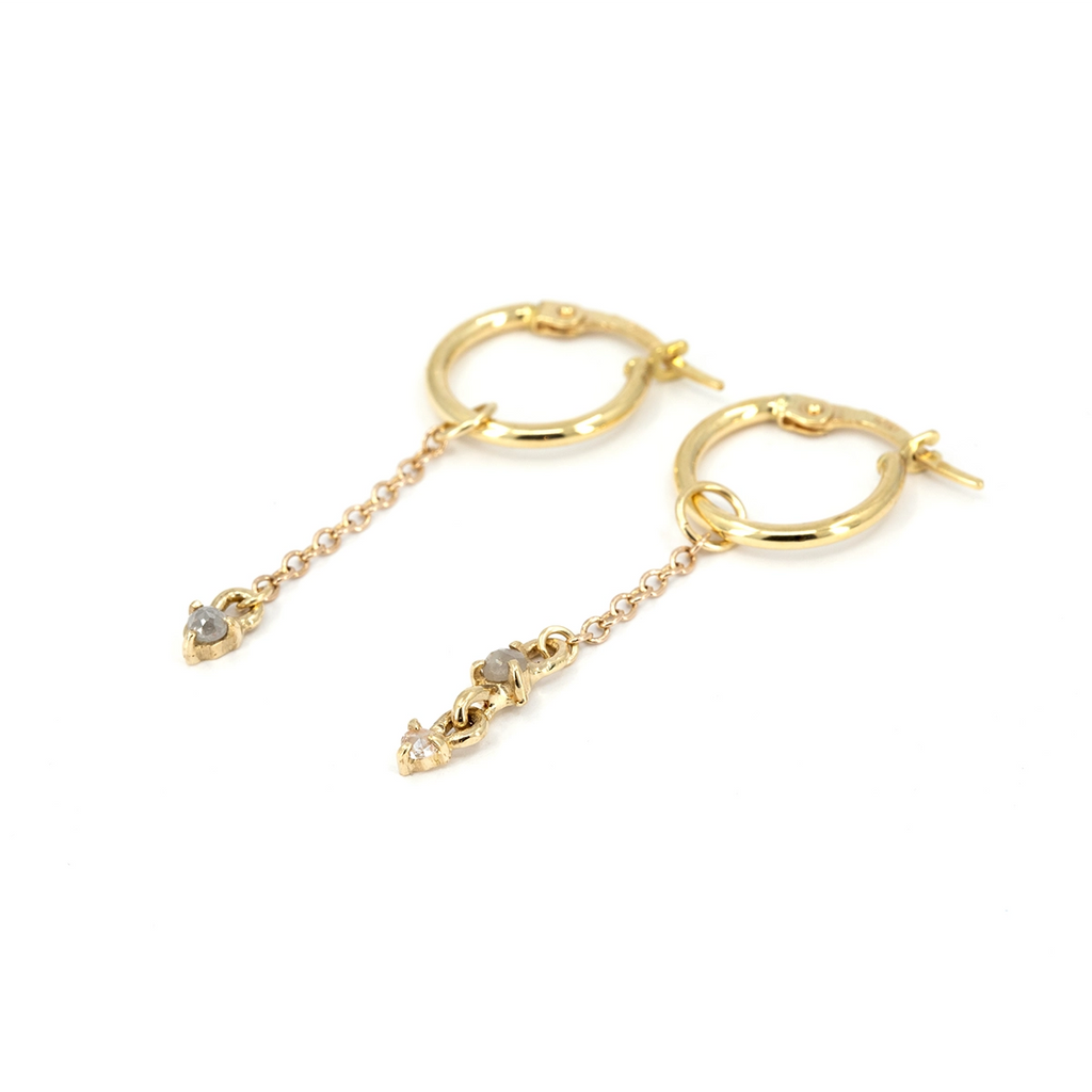 10k yellow gold asymmetrical hoop earrings by Toronto designer Nadia Werchola, featuring two natural rose-cut grey diamonds and one rose-cut white diamond on delicate dangling chains, shown on a white background, available at Ruby Mardi in Montreal.