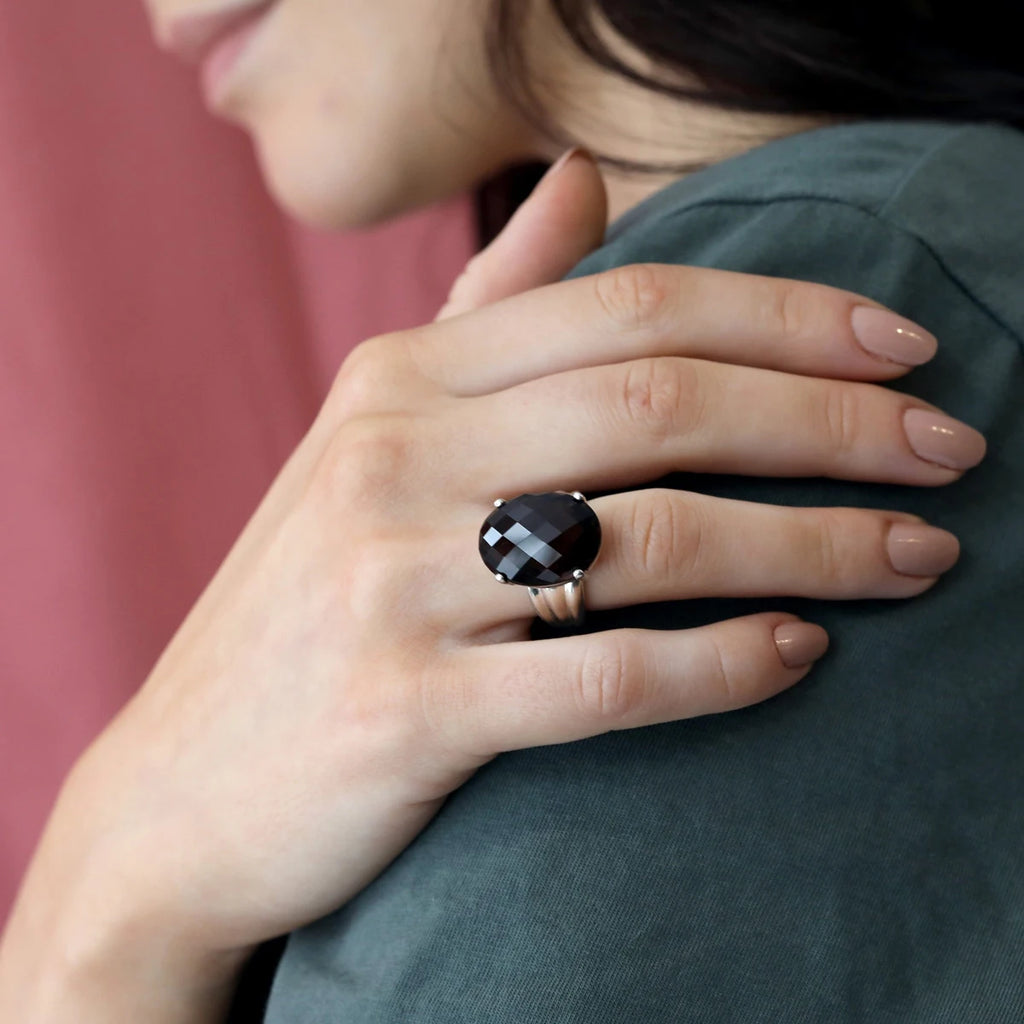 Woman wearing a statement ring with a large oval-shaped dark brown gem set in silver. Made in Canada by independent jewelry designer Bena Jewelry, this unique piece of jewelry is a one-of-a-kind creation and available for sale at the Ruby Mardi jewelry store in the Villeray and Rosemont neighborhood of Montreal.