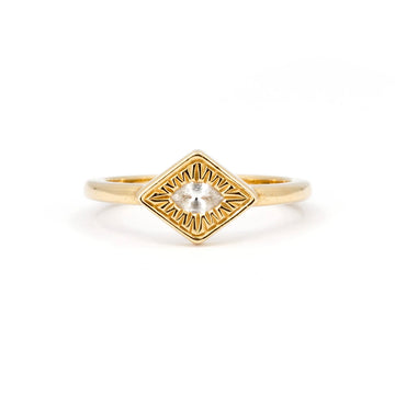 Yellow gold signet engagement ring with hand engraved details around the central stone, a marquise white sapphire. This engagement ring is a creation from designer Savannah Jones. It is seen photographed on a white background. 