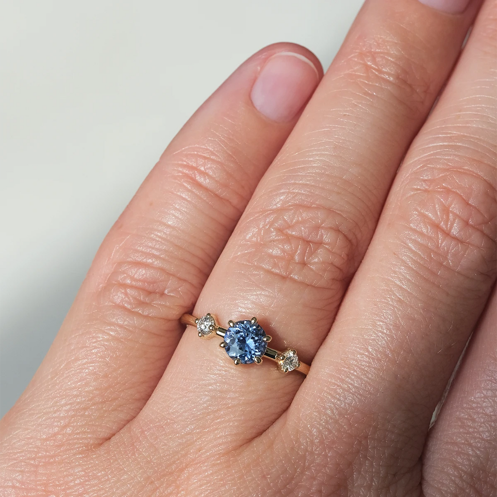 Light blue sapphire and diamond engagement ring worn on hand. Handmade in Montreal by Maksym Jewelry, available at Ruby Mardi.