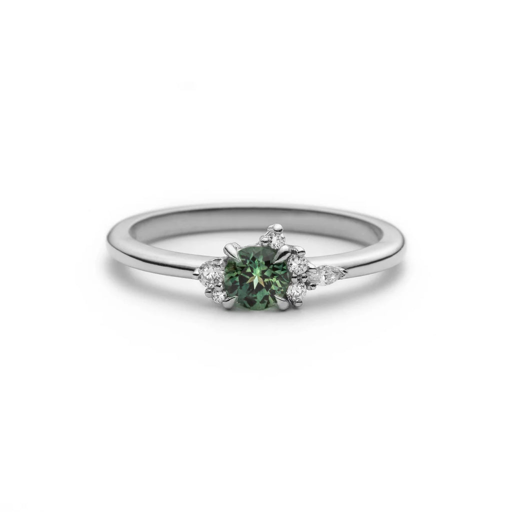 Little Folie engagement ring in 18k white gold with a round teal sapphire and diamond cluster by Justine Quintal, Ruby Mardi.