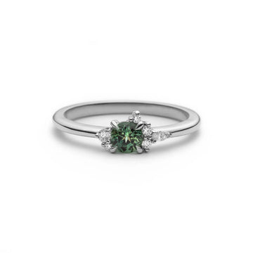 Little Folie engagement ring in 18k white gold with a round teal sapphire and diamond cluster by Justine Quintal, Ruby Mardi.