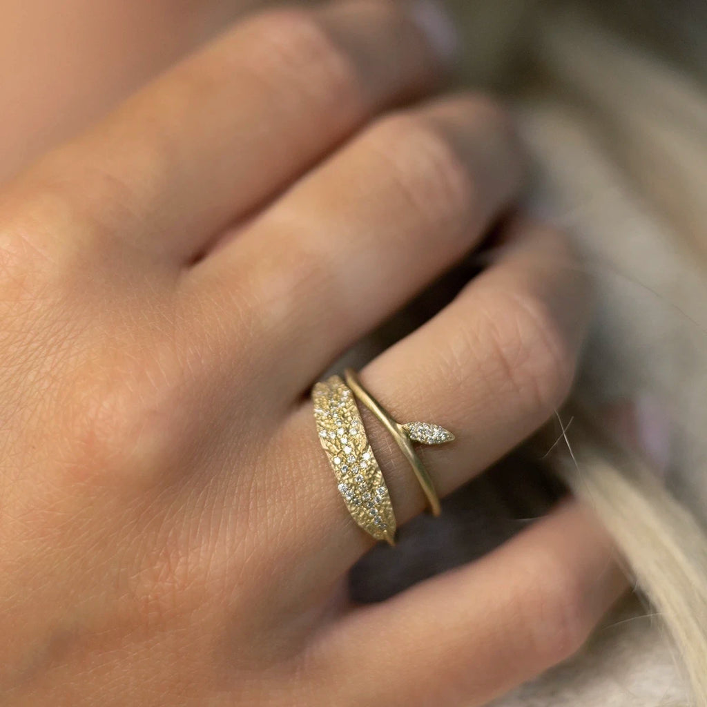 Woman's hand wearing a set of yellow gold ring with small diamonds in a delicate and organic style. Bridal jewelry made in Canada by Fluid Jewelry.