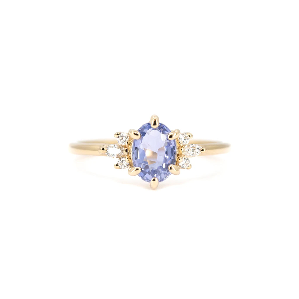 Front view of a light blue sapphire engagement ring with side diamonds in 14k yellow gold. Maksym Jewelry design, available at Ruby Mardi, Montreal.