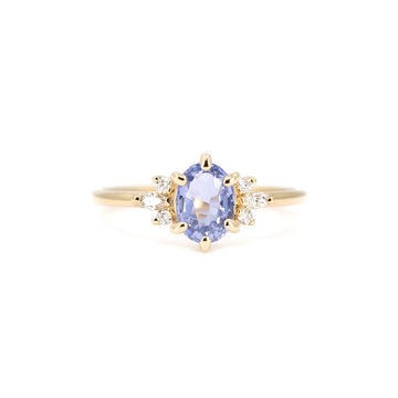 Front view of a light blue sapphire engagement ring with side diamonds in 14k yellow gold. Maksym Jewelry design, available at Ruby Mardi, Montreal.
