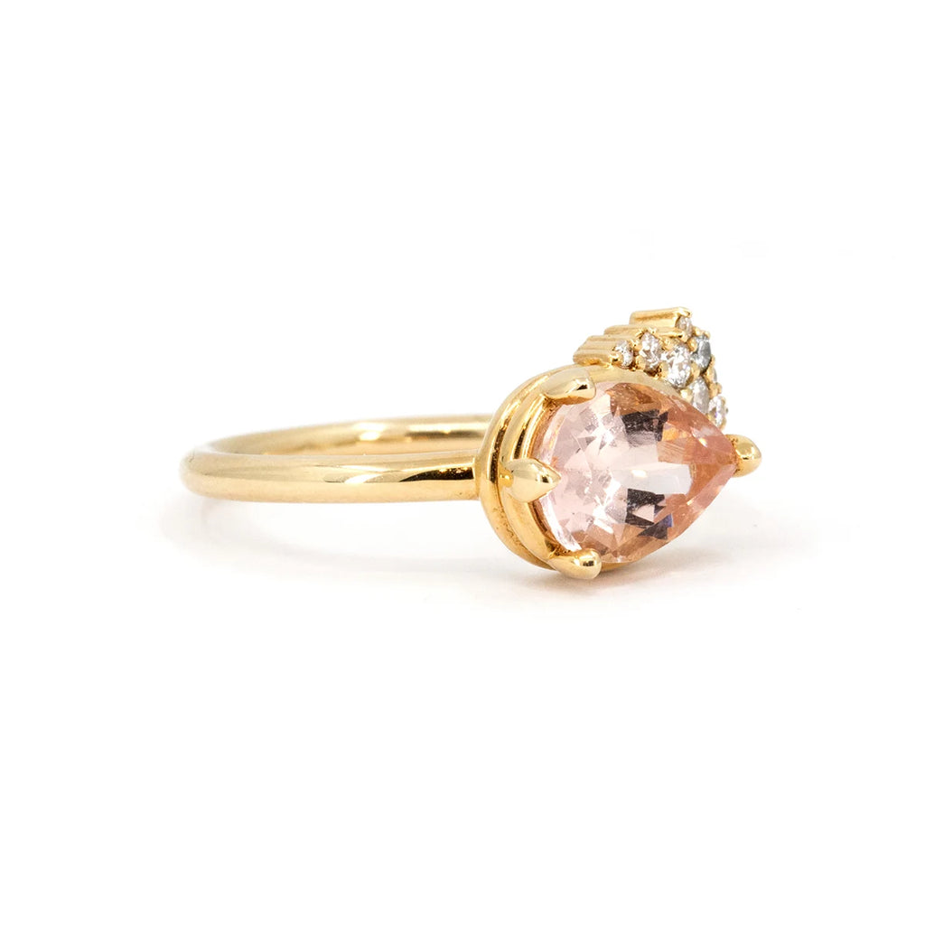 
Side view of a pear-shaped morganite engagement ring in soft pink hues, set in 14k yellow gold and complemented by a sparkling diamond cluster. A unique design handcrafted by Sheena Purcell, available at Ruby Mardi.