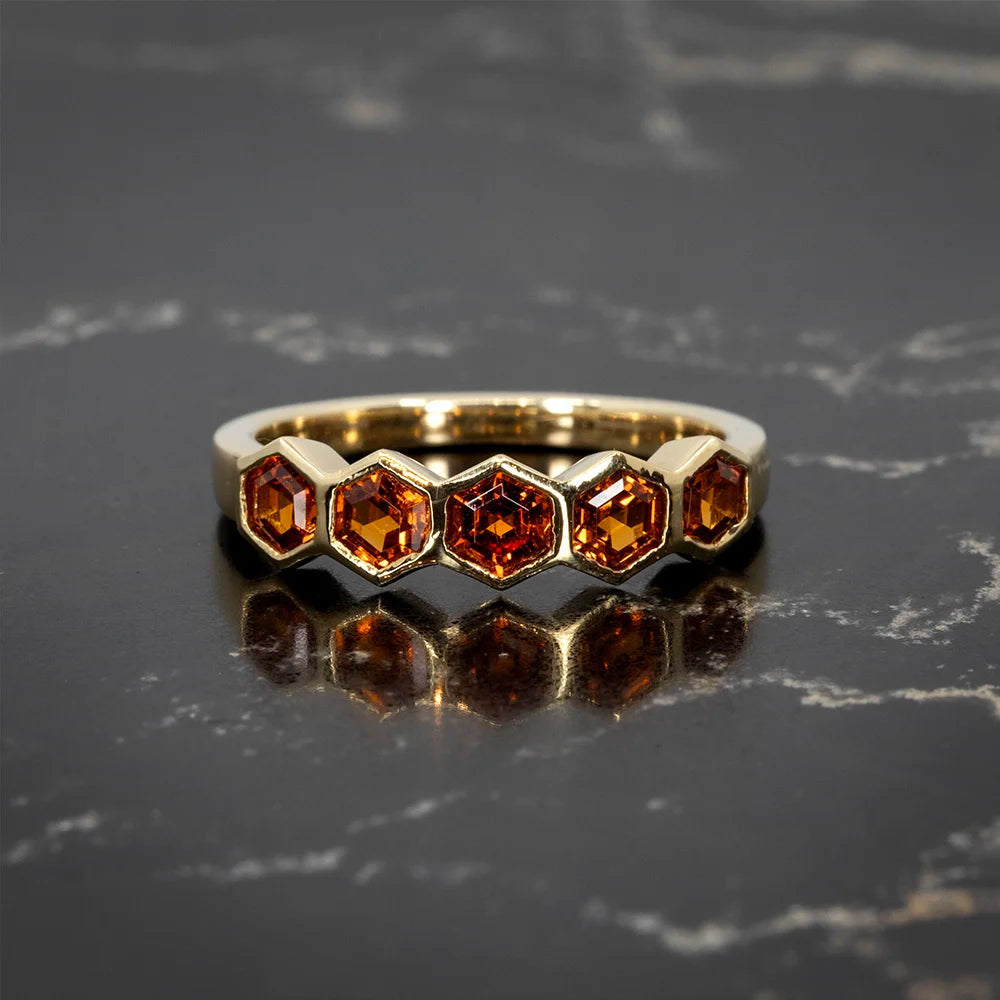 Gold ring by In the Light of Day, featuring five hexagonal orange gemstones in a sleek, modern setting. Available at Ruby Mardi, a fine jewelry gallery in Montreal.