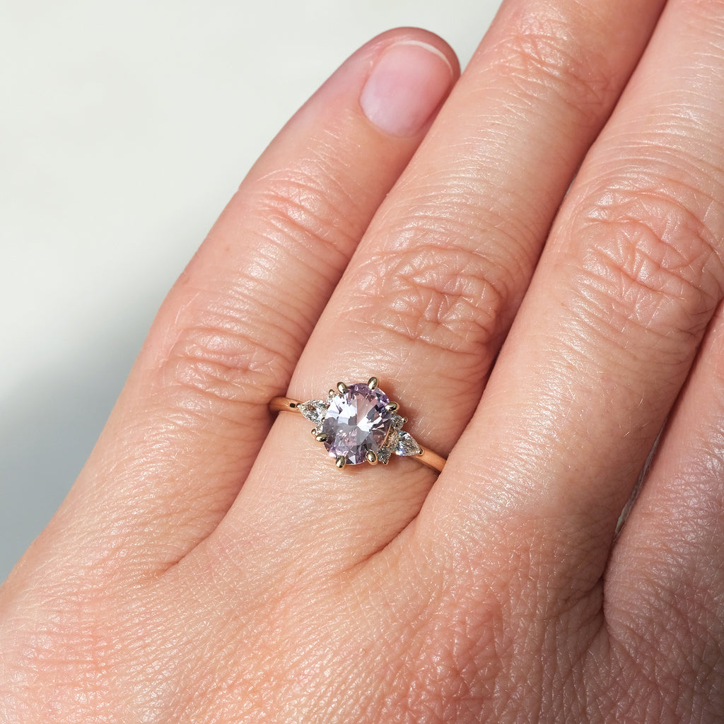 Lilac sapphire ring with diamond accents in yellow gold, worn on hand. Handmade in Montreal by Maksym Jewelry, available at Ruby Mardi.