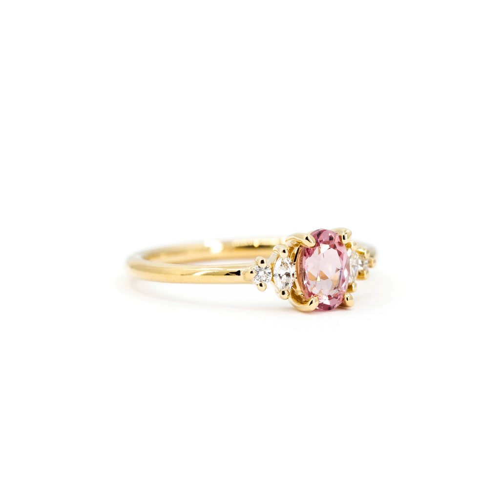 Malaya garnet and diamond engagement ring in 14k yellow gold, handcrafted by Maksym for Ruby Mardi in Montreal. Shown from a side angle on a white background.