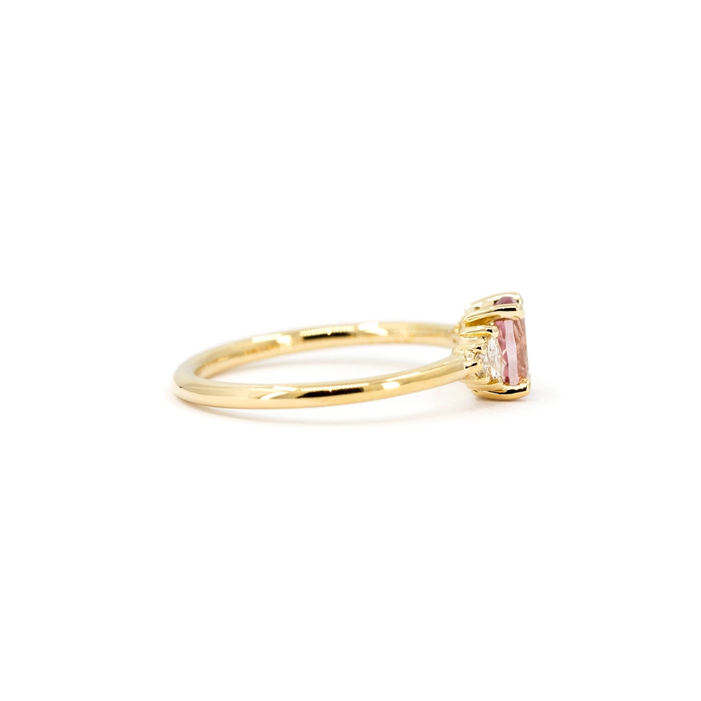 Side view of pink Malaya garnet engagement ring with diamond accents and open prong setting, crafted in yellow gold by Maksym, available at Ruby Mardi, fine jewelry store in Montreal, Canada.