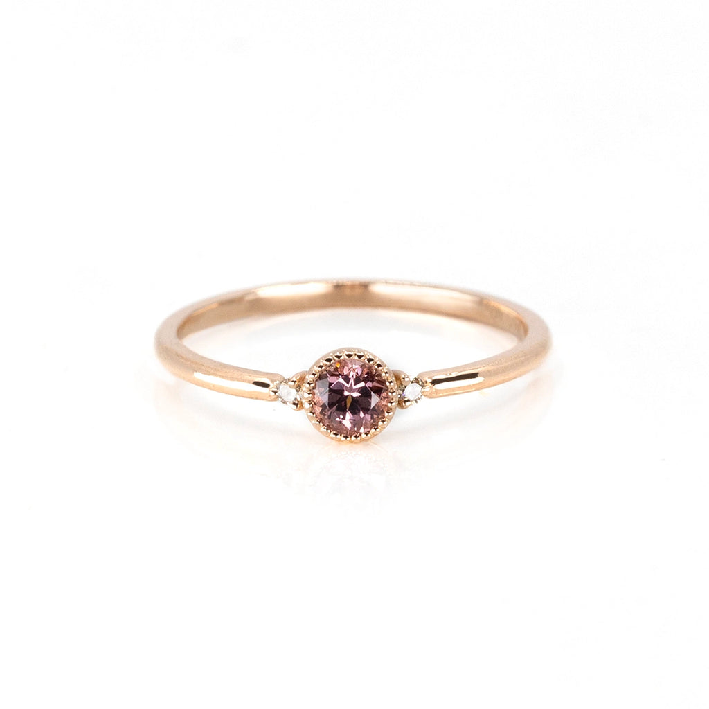 Malaya Garnet rose gold ring with a vintage vibe (thanks to the miligrain details on the bezel set) with 2 Canadian diamonds of a champagne color on each side. This engagement ring is photographed on a white background and was handmade in Canada by Atelier Emige.