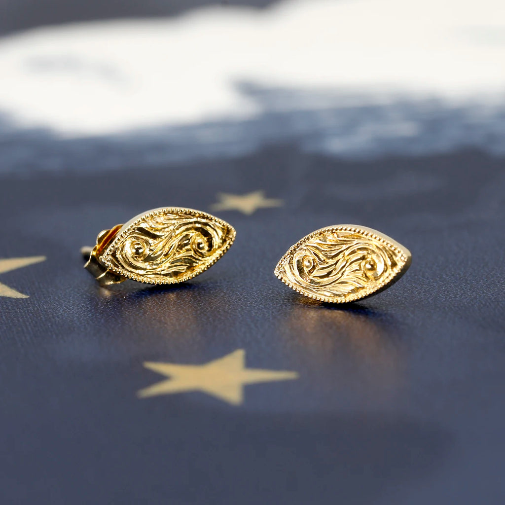 14k yellow gold marquise-shaped earrings photographed against a dark blue sky background, with two gold stars and a white cloud visible. The elegant design of the earrings stands out beautifully against the celestial backdrop.
