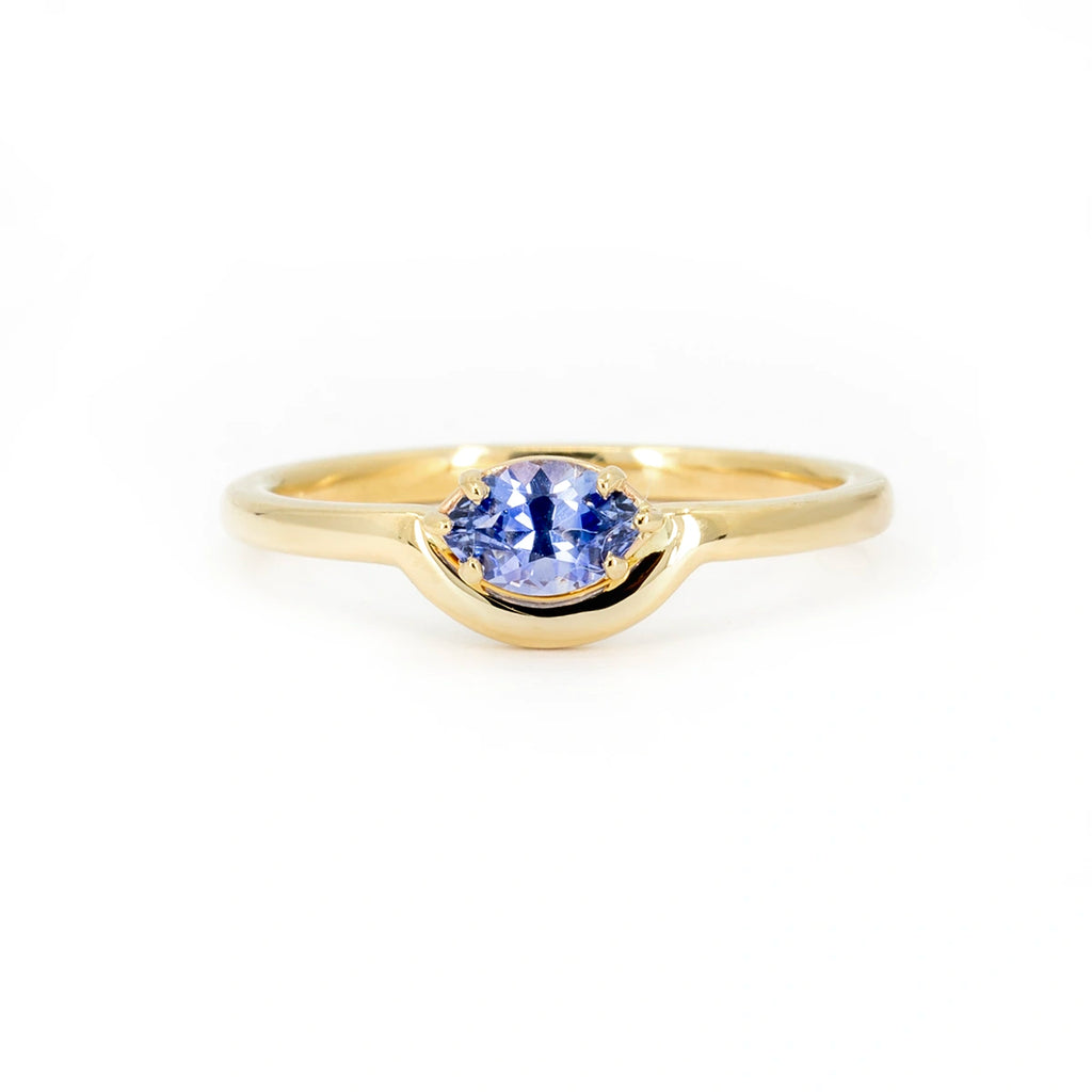 A lovely engagement or right-hand ring featuring a marquise-cut blue sapphire with a half-moon-shaped band around the gemstone. This creation is a one-of-a-kind piece of jewelry from independent American brand In the Light of Day Jewelry. This unique ring is available only at Ruby Mardi, a Canadian jewelry store located in Montreal's Little Italy.