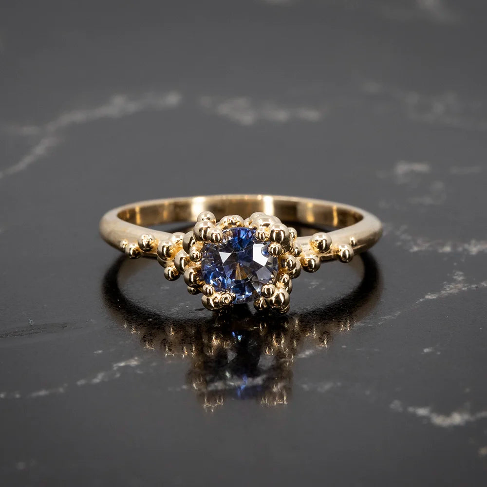 Elegant blue sapphire ring by Meg Lizabet, featuring intricate gold bead detailing in an organic-inspired design. Available exclusively at Ruby Mardi, Montreal.