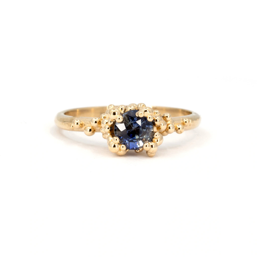 Organic-inspired ring featuring a blue sapphire surrounded by textured gold accents, evoking natural forms. Part of Ruby Mardi's Organic Jewelry collection, designed in Toronto.