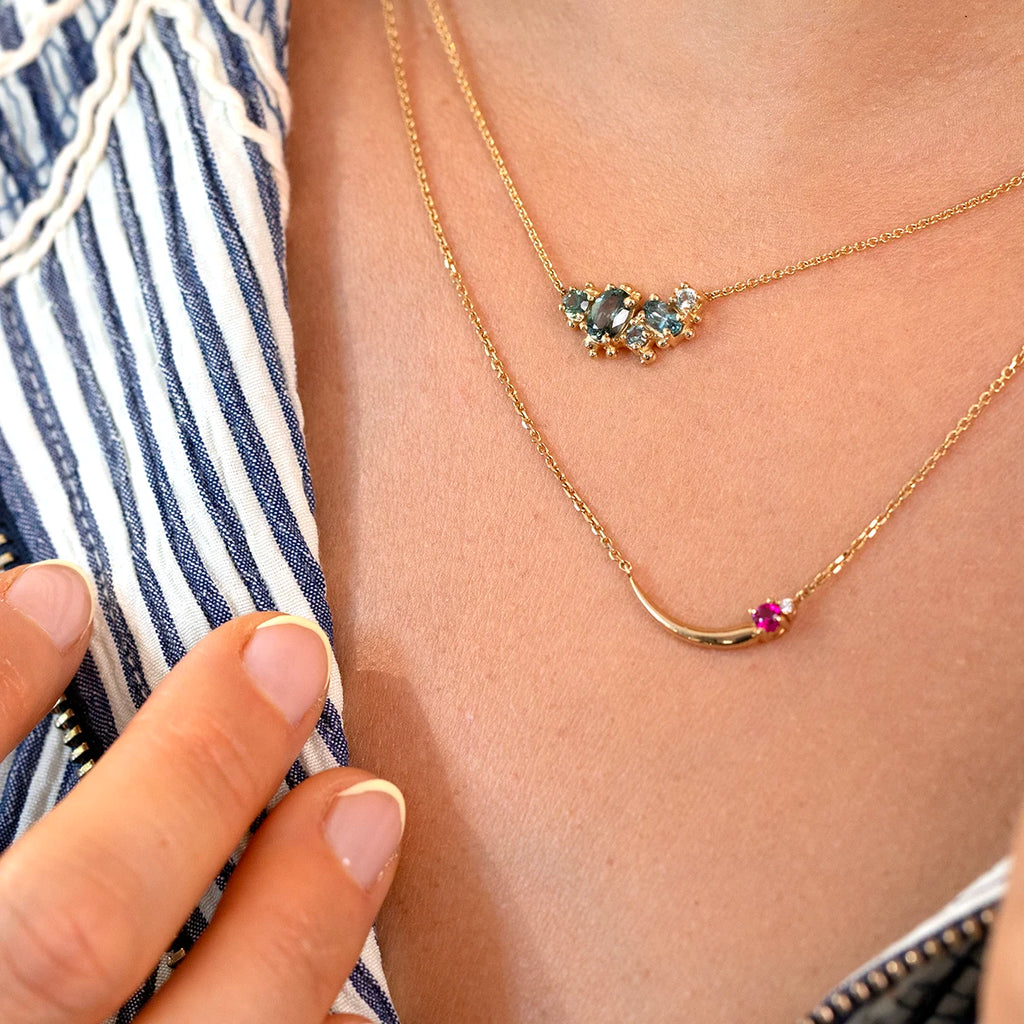 Montana sapphire cluster pendant necklace in 14k yellow gold, handcrafted by Canadian designer Meg Lizabet. Unique fine jewelry layered with a pink sapphire necklace, available at Ruby Mardi Montreal.