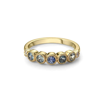 Splendid wedding ring with round-shaped teal-colored sapphires in a bezel setting with a delicate miligrain, handmade by the jeweler Bramston Goldsmithing, this elegant bridal ring is an exclusive from the Ruby Mardi jewelry store in Montreal, specialist in unique jewelry one of their kind made in Canada.