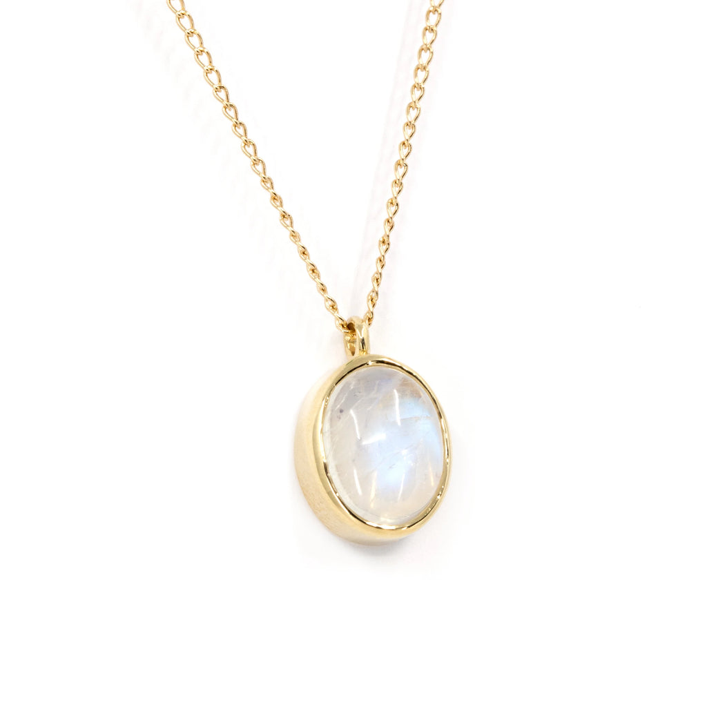 Side view of a 10k yellow gold pendant featuring an oval cabochon moonstone, bezel set, showcasing its elegant volume. Handcrafted by Rooz Jewelry and available at Ruby Mardi, this classic piece highlights the beauty of its natural gemstone.