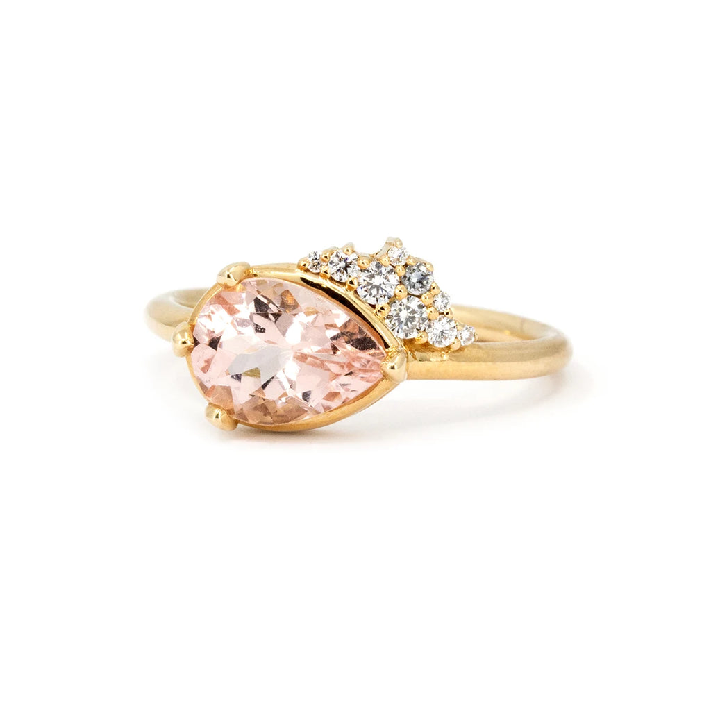 Pear-shaped light pink morganite engagement ring, complemented by a dazzling diamond cluster, set in 14k yellow gold. Designed and handcrafted in Montreal by Sheena Purcell for Ruby Mardi.
