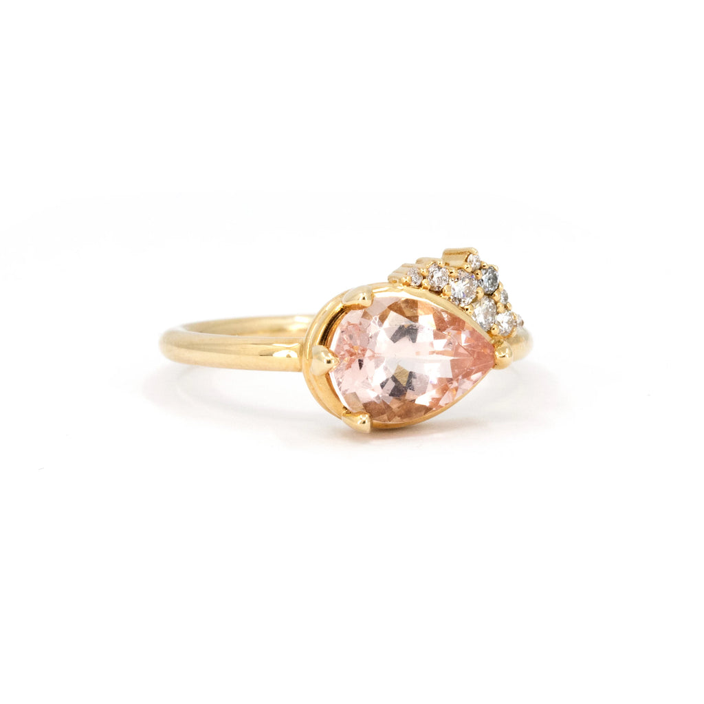 Pear-shaped morganite engagement ring set in 14k yellow gold, accented with a sparkling diamond cluster. A romantic and modern design, handcrafted by Sheena Purcell in Montreal, available at Ruby Mardi.