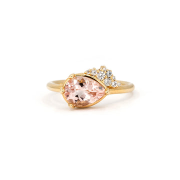Pear-shaped morganite engagement ring set in yellow gold, featuring a diamond cluster accent. Designed and handcrafted by Ruby Mardi in Montreal, the best jewelry store in Canada. 