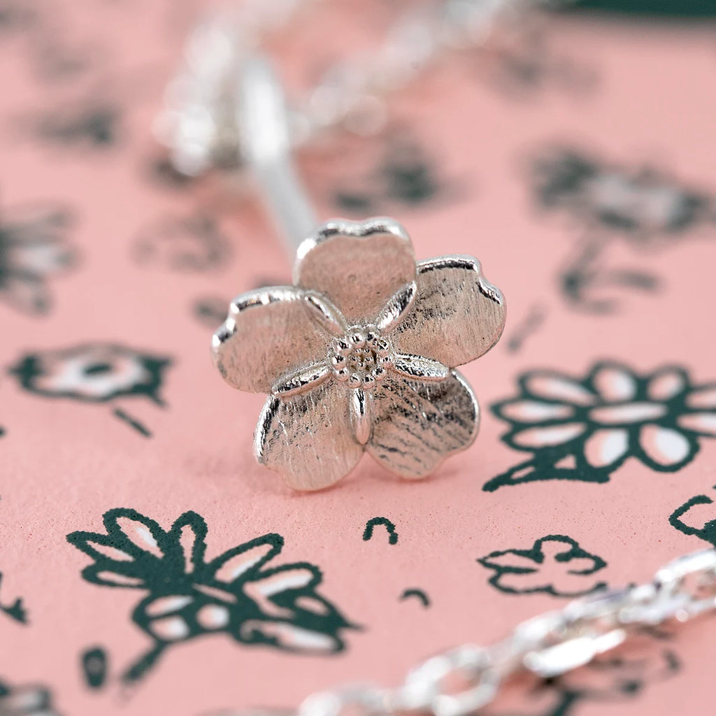 Close up of the white gold myosotis forget me not pendant by Fleurs Sauvages Qc, showing detailed petals and center texture. Handmade botanical jewelry available at Ruby Mardi in Montreal.