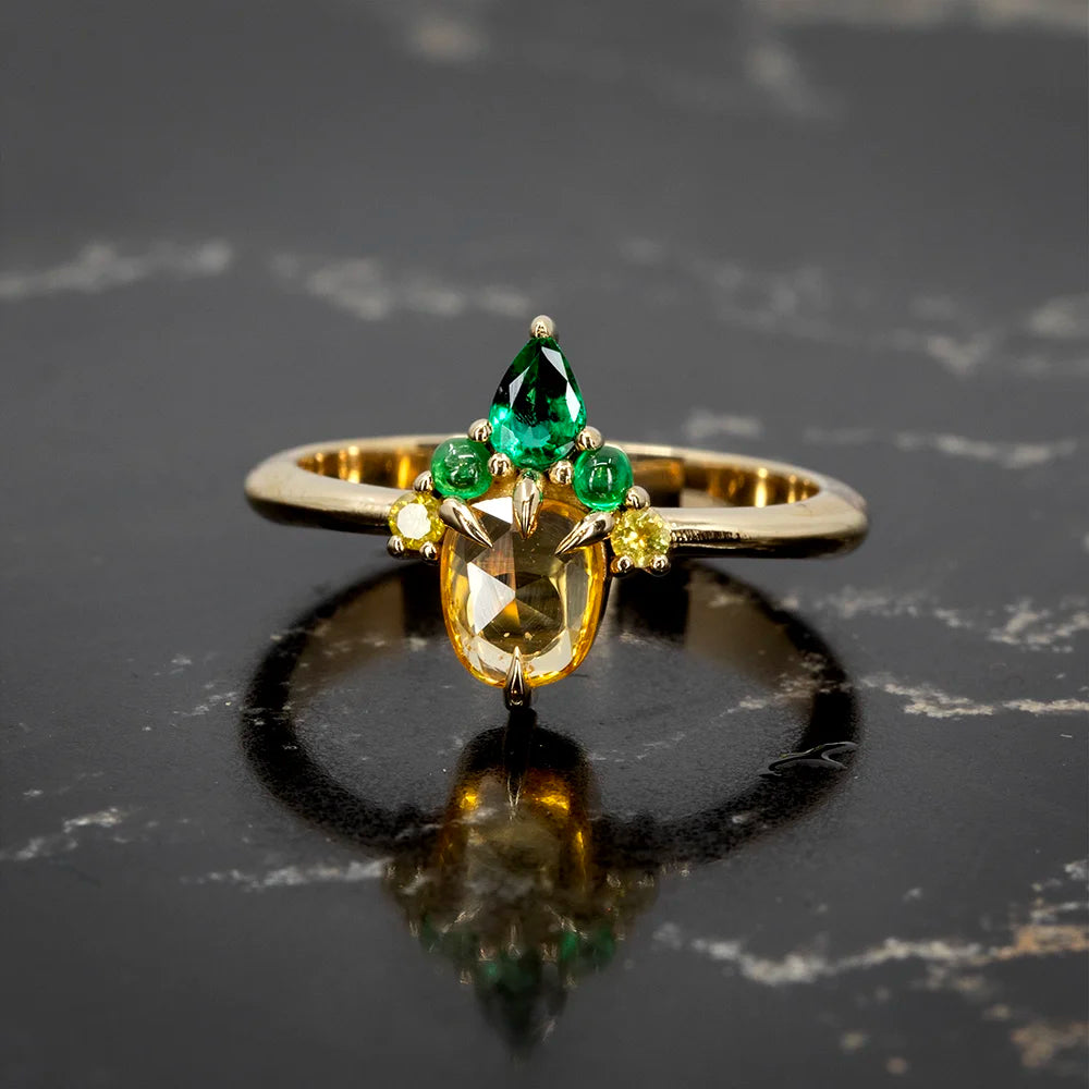 Statement ring by Nadia Werchola showcasing a central yellow sapphire, 2 natural yellow diamonds, and 3 vibrant emeralds. Available at Ruby Mardi, Montreal.