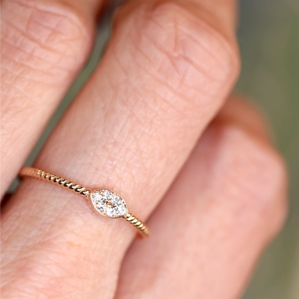 Close-up of a rose gold ring with twisted band and marquise-shaped cluster of natural white diamonds, worn on a finger. Handcrafted by Oleg Leybman in Toronto, available at Ruby Mardi in Montreal.