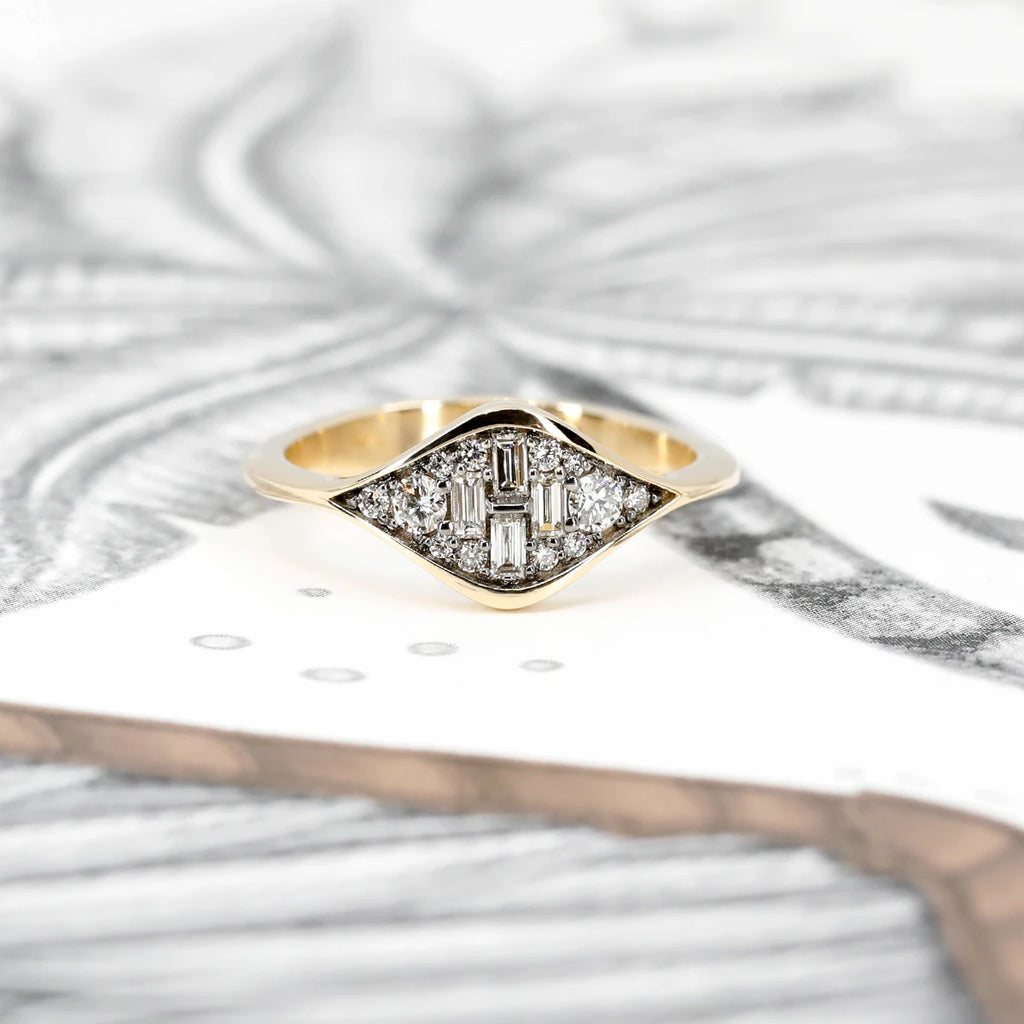 Front view on a white and black background of an alternative bridal ring in yellow gold featuring many natural white diamonds arranged in a tear drop shape. Handmade in Toronto, this engagement ring or right hand ring is available in Montreal at Ruby Mardi.