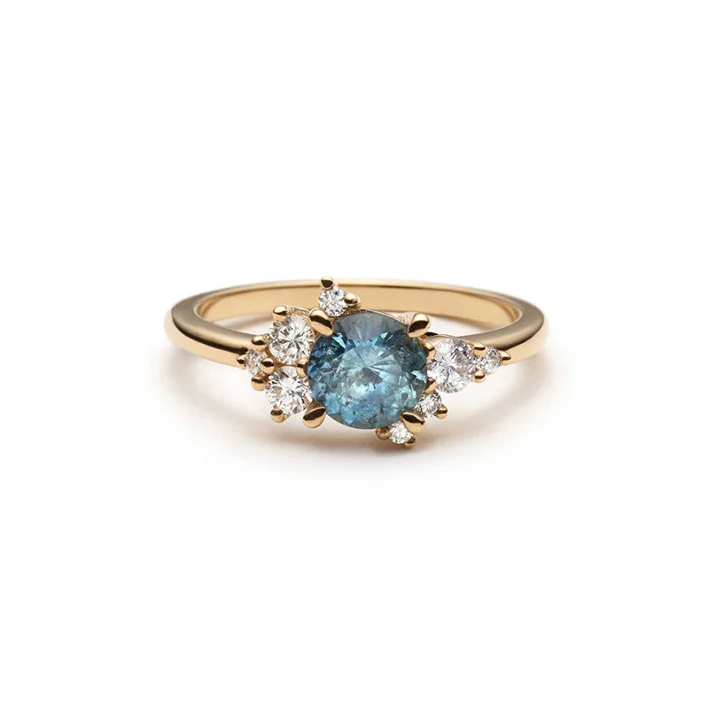 Yellow gold asymmetrical ring featuring a round navy blue sapphire and scattered diamond accents. Handmade by Justine Quintal and available at Ruby Mardi.