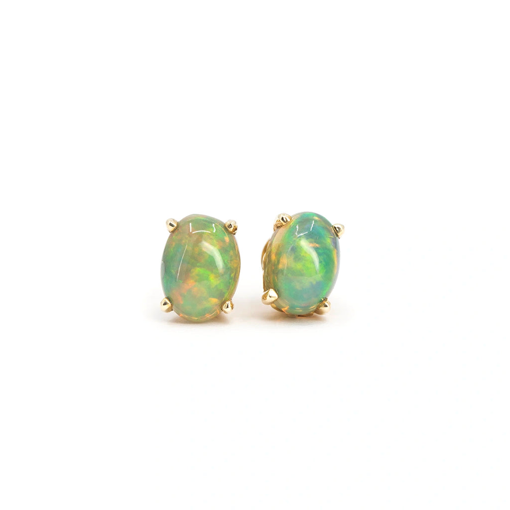 Pair of oval-shaped natural opal stud earrings in 14k yellow gold handmade by Rooz Jewellery in Toronto, and available at Ruby Mardi, best jewelry store in Canada. Seen on a white background.