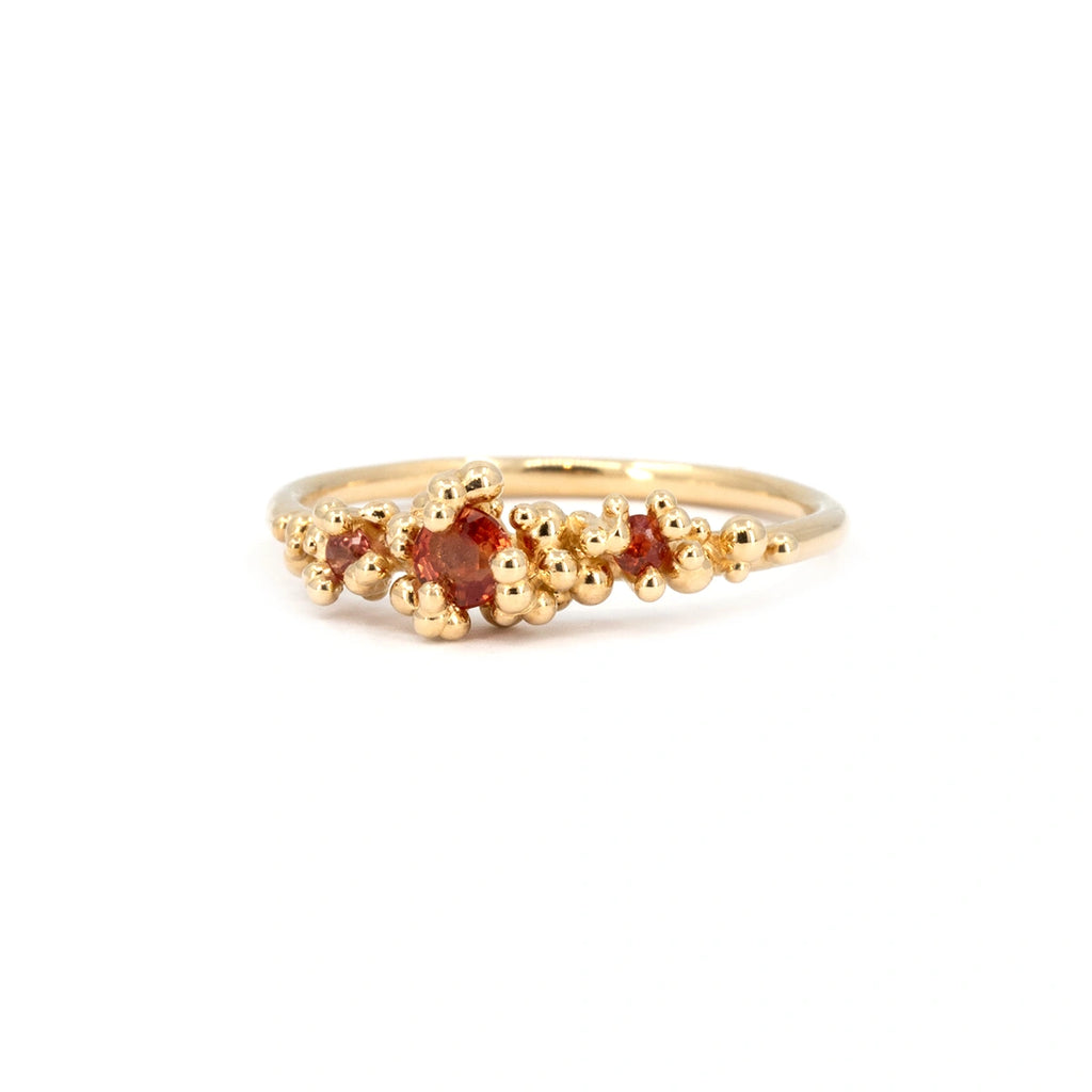 Handcrafted gold ring featuring three orange sapphires surrounded by organic gold bead accents. Designed by Meg Lizabet for the Areia Signature Collection at Ruby Mardi. Made in Montreal, Canada.