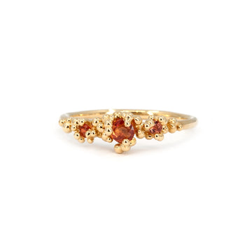 Organic-inspired gold ring featuring three vibrant orange sapphires surrounded by intricate gold bead detailing. Designed by Meg Lizabet for the Areia Signature Collection at Ruby Mardi. Handcrafted in Montreal, Canada.