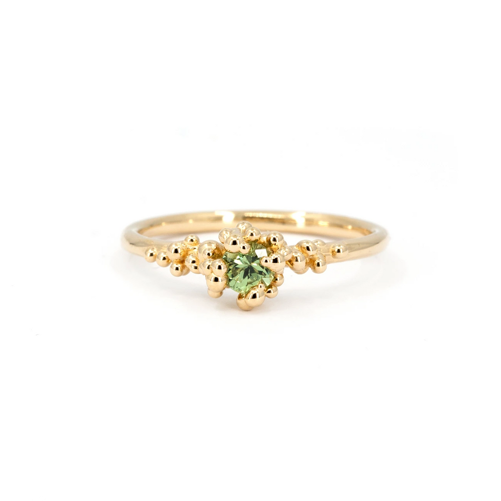 Organic engagement ring with light green sapphire and sculptural gold granules, handmade by Meg Lizabet. Contemporary fine jewelry photographed on white background, available at Ruby Mardi, Montreal.