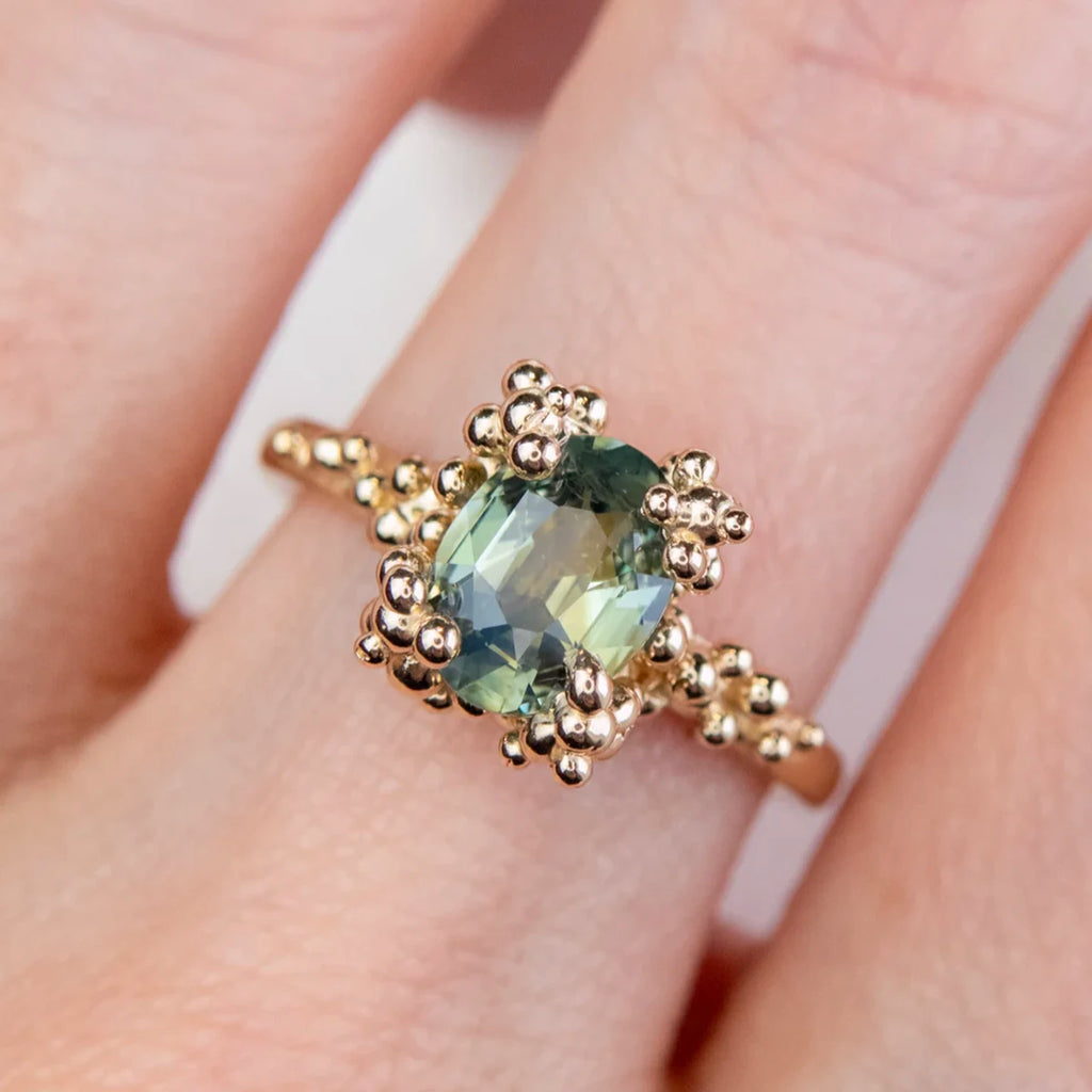 14k gold ring with oval green sapphire and gold granule setting, worn on hand. Designed by Meg Lizabet. One-of-a-kind engagement ring available at Ruby Mardi in Montreal.








