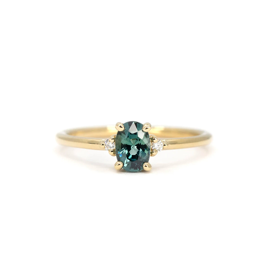 Oval teal sapphire ring with diamond accents in yellow gold, handmade in Montreal by Maksym Jewelry. Available at Ruby Mardi, designer fine jewelry store in Canada.