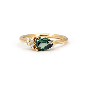 Pear-cut teal sapphire engagement ring in yellow gold with accent diamonds, designed by Ruby Mardi, an independent jewelry brand in Montreal, Canada.