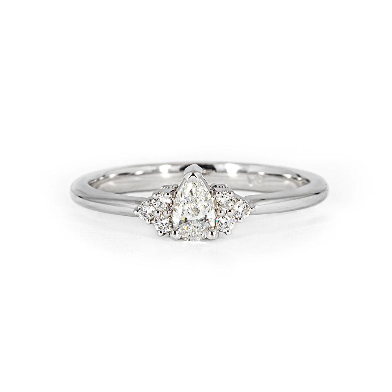 Experience timeless elegance with the 'Désir' engagement ring, featuring a pear-shaped diamond and three small round diamonds on each side, delicately set in white gold. Meticulously crafted in Montreal by Ruby Mardi, the premier bridal jewelry boutique, this classic and timeless design captures the essence of everlasting love. Discover the artistry of unique and bespoke wedding jewelry at Ruby Mardi, your specialist in one-of-a-kind creations, located in the Rosemont and Villeray neighborhoods.