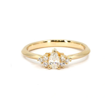 Dainty engagement ring in yellow gold featuring a pear-shaped diamond at the center, accented by clustered round diamonds. Handmade in Montreal by Ruby Mardi.