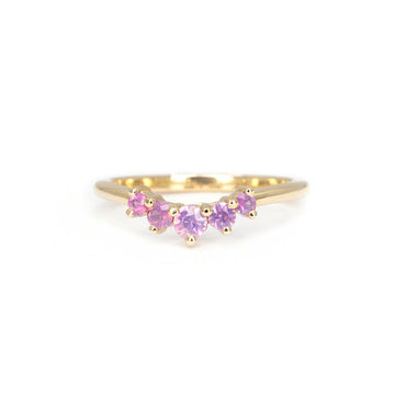 Pink sapphire contour band in 14k yellow gold, handcrafted by Emily Gill. Features five round heated pink sapphires from Vietnam in shared prong settings. Elegant stacking ring photographed on white background. Available at Ruby Mardi, fine jewelry store in Montreal, Canada.