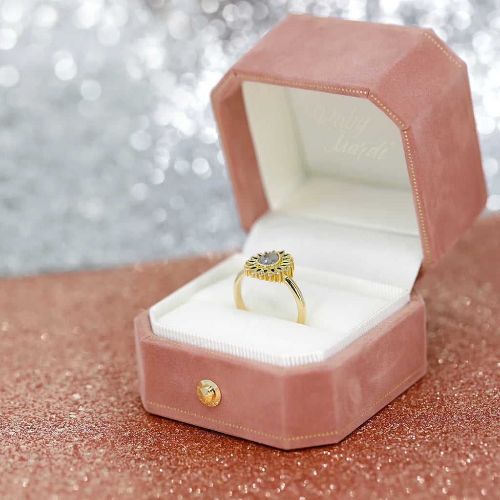 A one-of-a-kind alternative engagement ring with a pear salt and pepper diamond is photographed in a Ruby Mardi's velvet box. This pink box is photographed on a pink sequin background.
