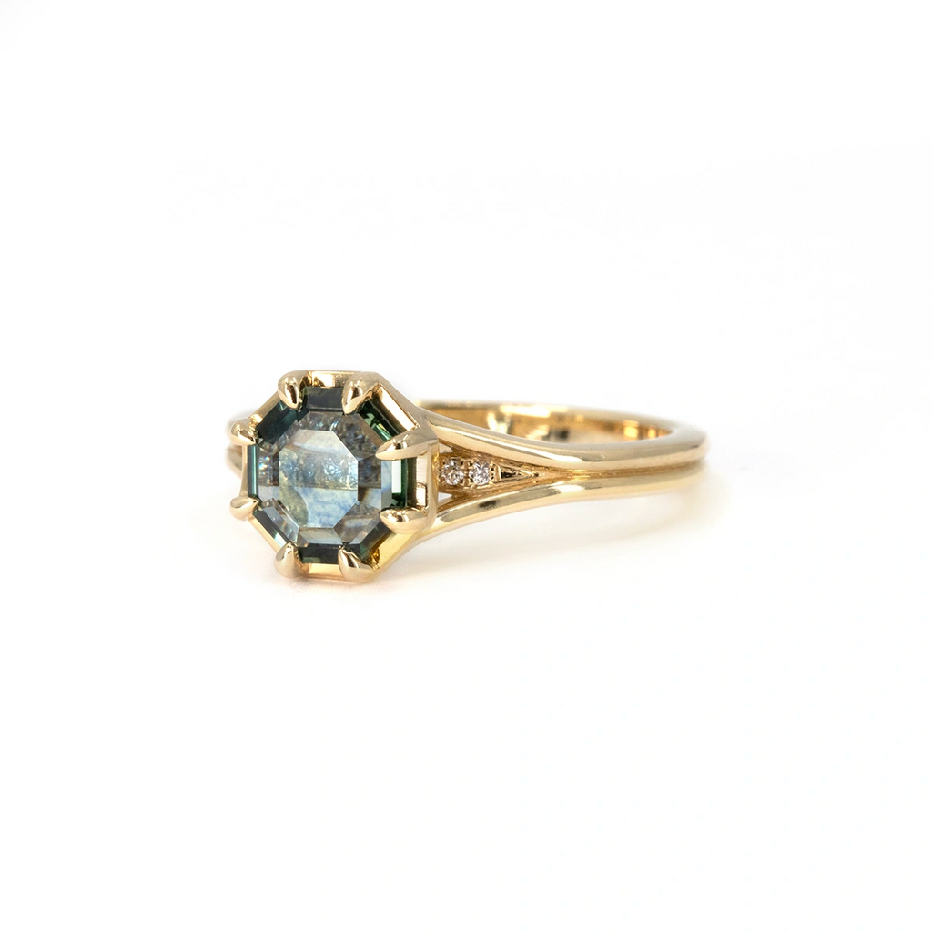 Close-up of Arden ring designed by Emily Gill, featuring a 1.19 ct octagonal portrait-cut Montana sapphire with a split shank 14k yellow gold band and diamond accents. One-of-a-kind fine jewelry available at Ruby Mardi in Montreal.