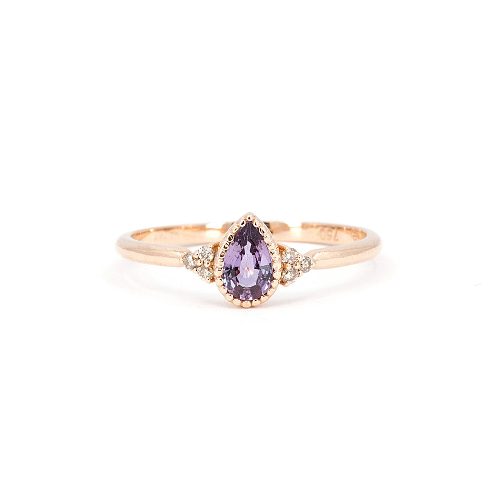 This pretty engagement ring is made with a pear-shaped purplish pink sapphire with a delicate bezel setting with a miligrain to give a vintage and refined style. This bridal ring is made by the jewelry designer Émigé in Montreal in collaboration with the Ruby Mardi jewelry store, a jewelry gallery specializing in wedding rings and jewelry from independent Canadian and Quebec designers.